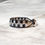 Thumbnail: cuff style leather bracelet in black and silver on marble countertop side view