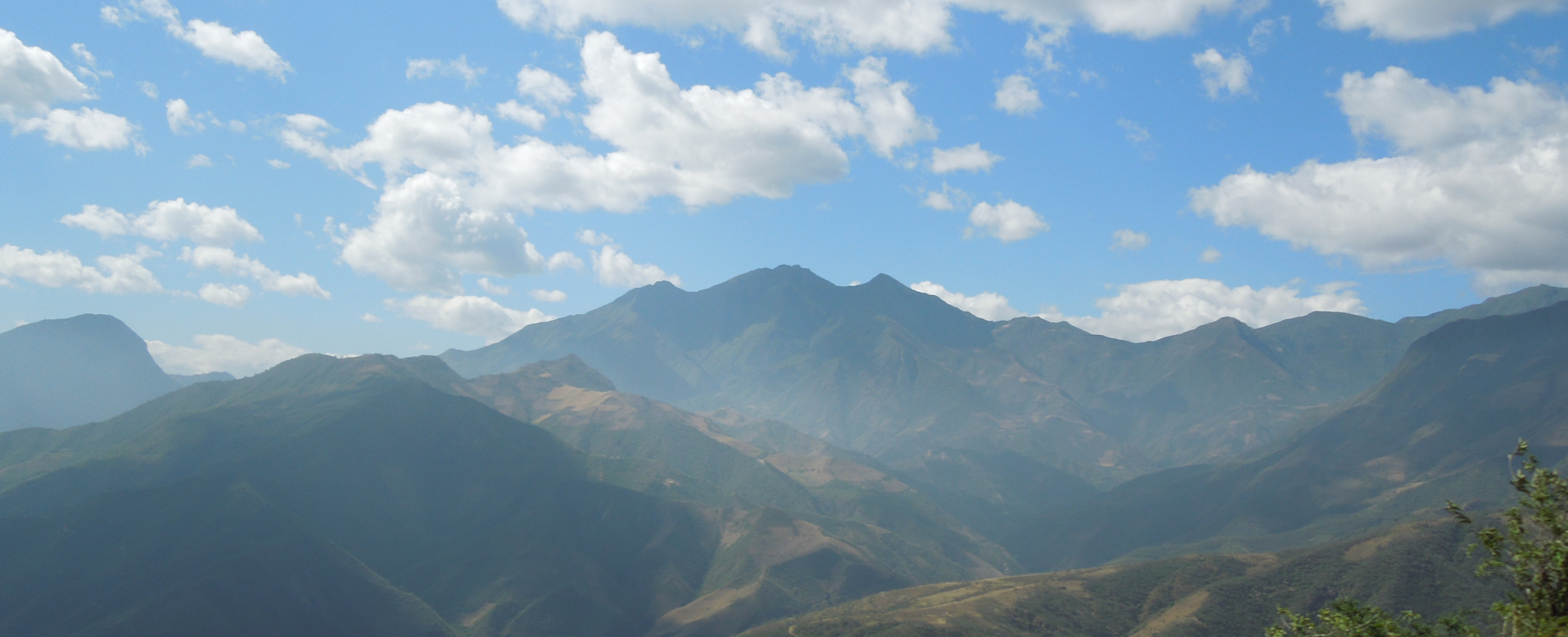 Green mountains beneath a blue sky in the Peru coffee-growing region
