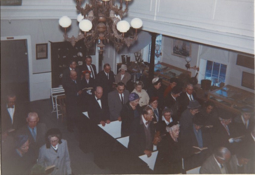 Group of people standing in a church hold books and singinging