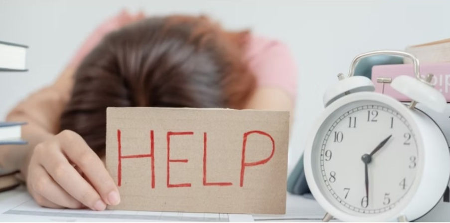 A person holding a help sign over whelmed at their desk