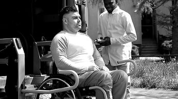 A man sitting in a wheelchair next to a van_edited.jpg