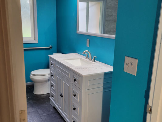 Modern bathroom with soothing blue walls, a white sink, and a mirror, providing a clean and inviting ambiance.