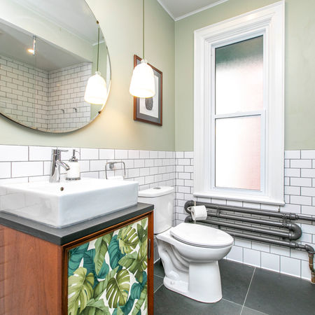 Bathroom with white subway tile, slate floors, custom vanity, and vintage mirror