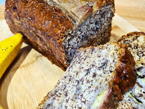 Freshly baked banana bread sliced on a wooden board with a golden crust and soft, moist crumb