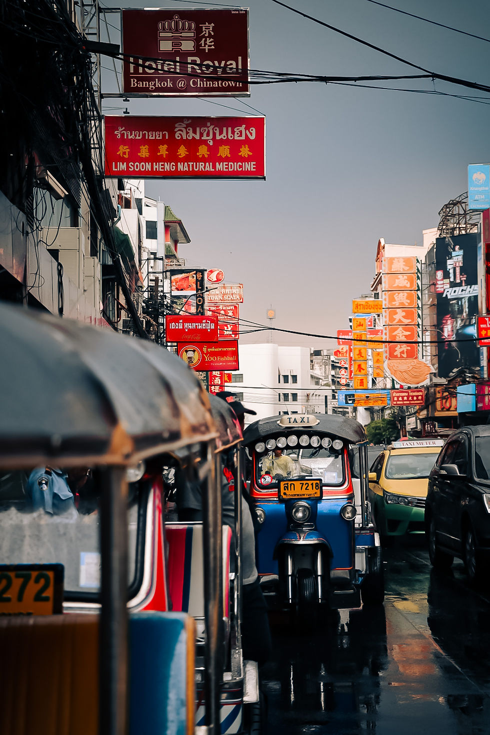 Blue tuk-tuk in early morning light surrounded by neon signs in Chinatown Bangkok