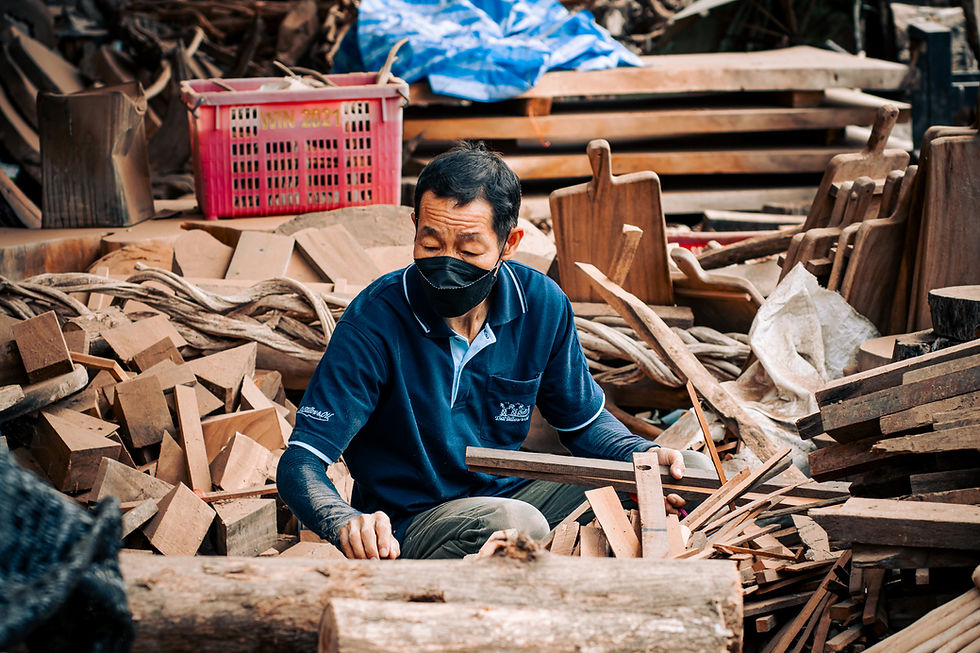 Thai worker wearing a mask sorting hardwood pieces in Ban Tawai, Chiang Mai’s artisan village.