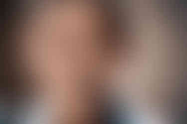 Portrait of an elderly Thai man smiling, showing deep facial lines and warm eyes, taken during a trusted street interaction.