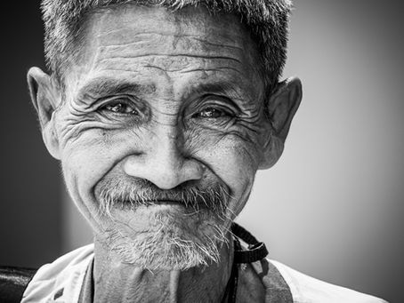 Black and white close-up street portrait of a smiling elderly Thai man with a goatee, Canon 90D 85mm f/1.8 Chiang Mai Thailand