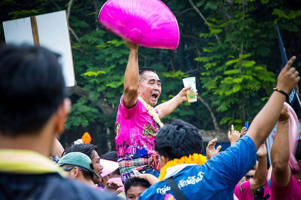 Victory tastes like beer and joy. Lifted above the crowd, fan in one hand, drink in the other—he celebrates not just a rocket’s flight, but the spirit of teamwork and festival pride.