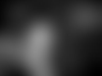 Black and white portrait of a young boy holding a pillar, with half his face in shadow, conveying introspection and quiet strength.