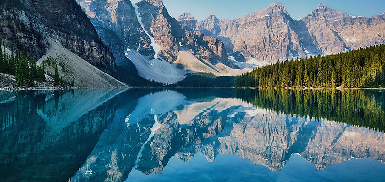 Panaramic view of a mountain range with its reflection in the blue lake below it. | CanStart Immigration