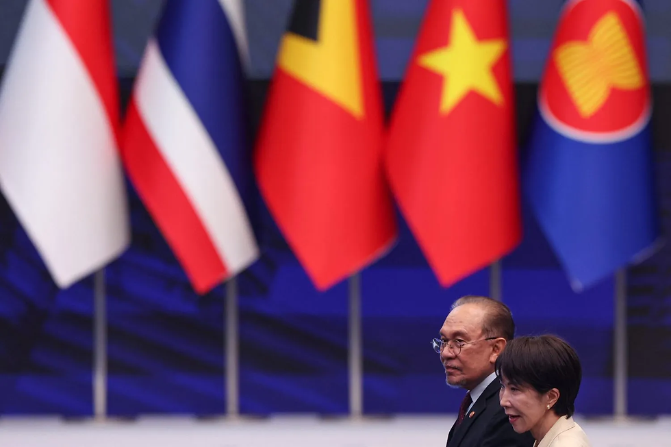 Malaysian Prime Minister Anwar Ibrahim and Japanese Prime Minister Sanae Takaichi walk past national flags during the ASEAN summit in Kuala Lumpur, Malaysia, on Oct. 26. CHALINEE THIRASUPA/POOL/AFP via Getty Images