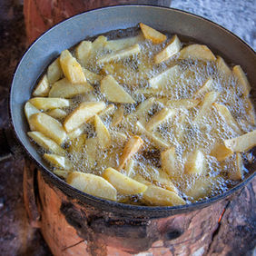 Golden french fries frying in oil, traditional cooking method