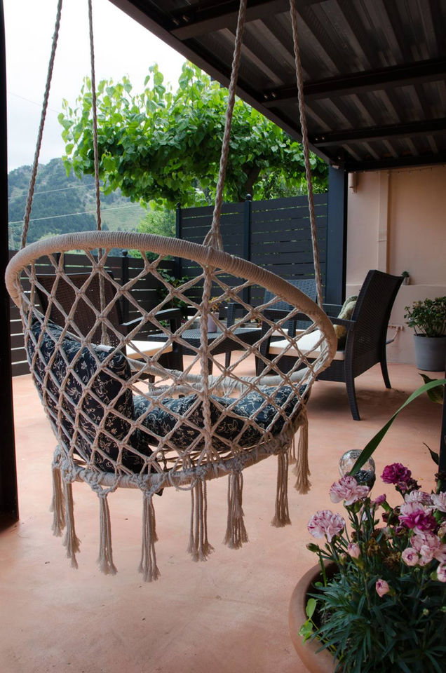 Cozy swing chair hanging on a porch with flowers and a mountain view.