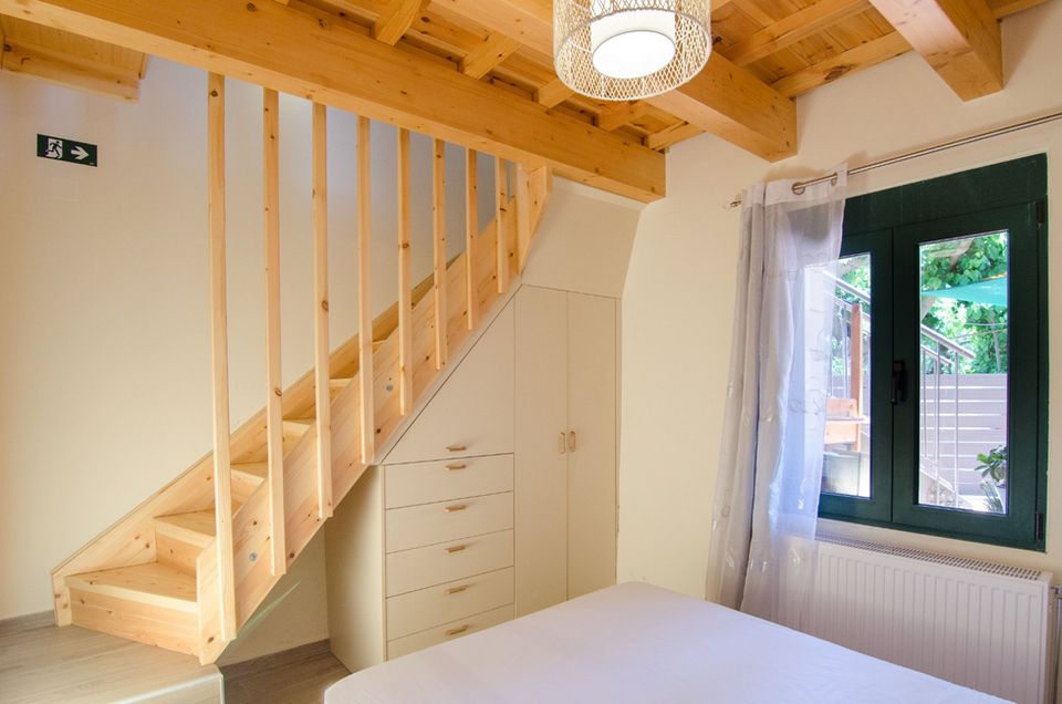 Stairs and a wardrobe under the stairs in a bedroom with a large bed.