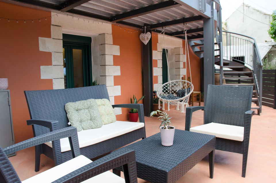 Terrace with a sofa, chairs, a table, and a swing.
