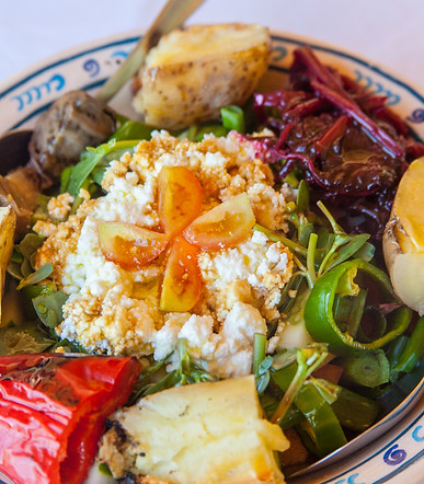 A salad served on a plate with traditional cheese and vegetables.
