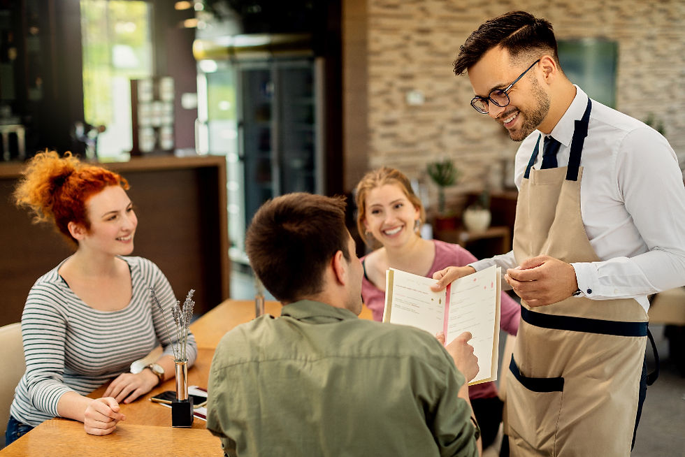 Trei clienți zâmbitori la o masă într-un restaurant, interacționând cu chelnerul care le prezintă meniul. Fundal modern și luminat.