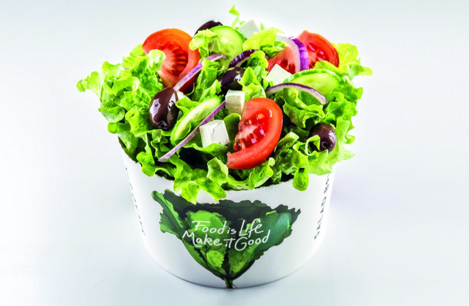 Salată verde cu roșii, castraveți, măsline și feta într-un bol alb. Text vizibil: "Food is Life. Make it Good". Fundal alb simplu.