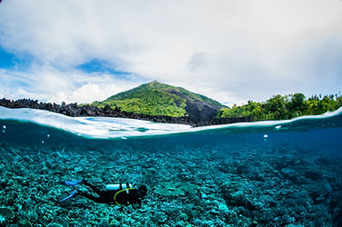 Diver exploring vibrant coral reef near volcanic island
