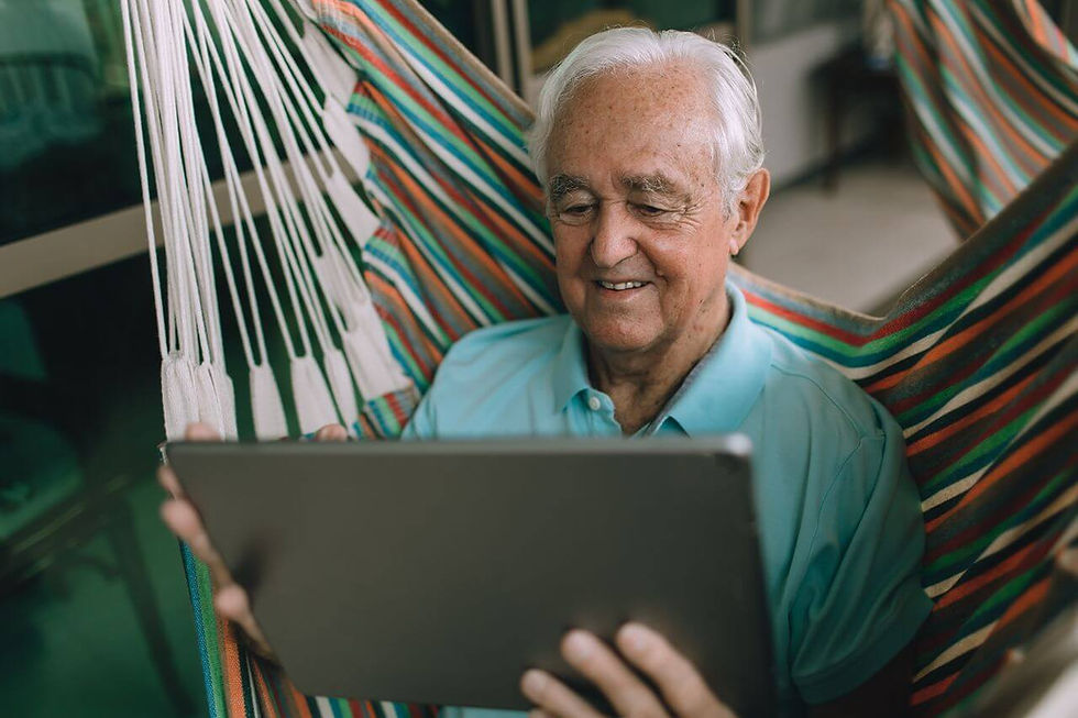 An elderly man smiling with his ipad in hand