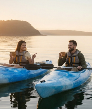 Smiling couple in kayaks with drinks at sunset