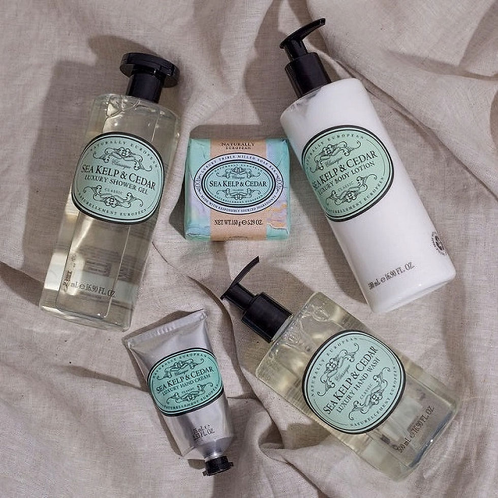 Five "Sea Kelp & Cedar" bath products on beige fabric. Includes shower gel, body lotion, hand wash, soap, and hand cream with green labels.