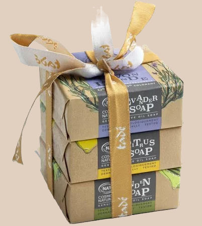 A stack of three wrapped soap bars tied with gold and white ribbon. Labels read "Lavender Soap", "Citrus Soap", and "Golden Soap".