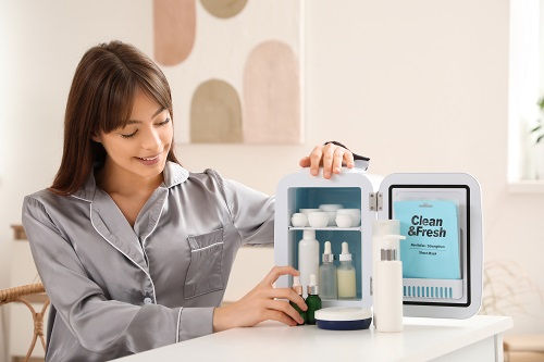 Woman in gray pajamas organizes toiletries in a small case labeled Clean & Fresh on a bright table.
