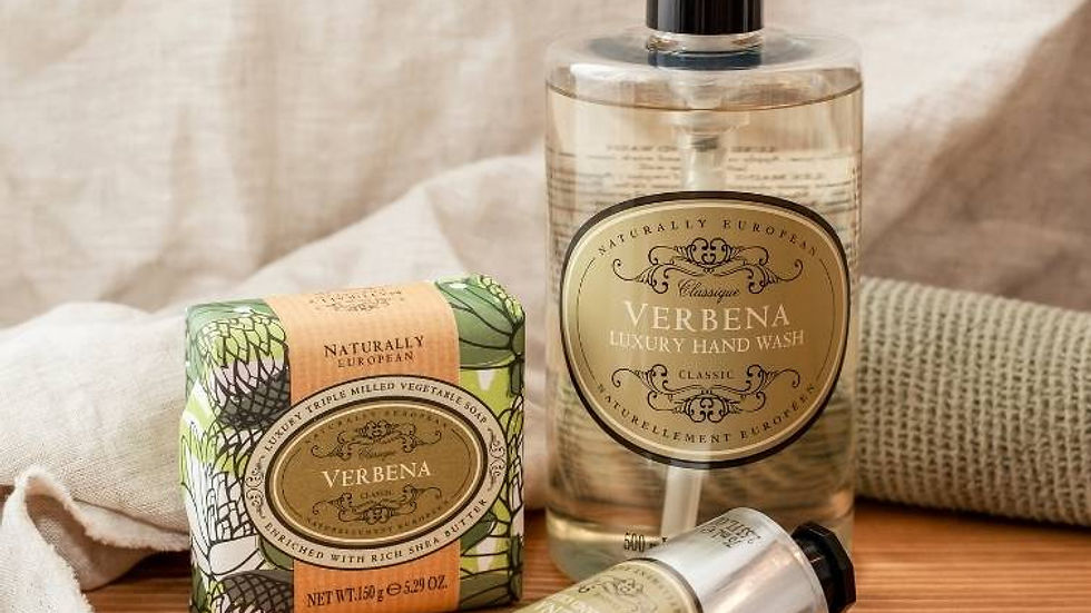 Verbena soap, hand wash, and lotion on a wooden surface with beige cloth backdrop, in warm natural light.