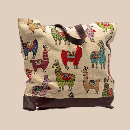 Canvas tote bag with colorful llama patterns on a beige background, brown leather accents, displayed against a plain backdrop.