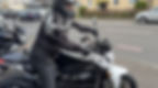 Motorcyclist drives up on white e-motorcycle