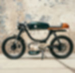 Metorbike, ein Cafe-Racer, vor weißer Steinmauer