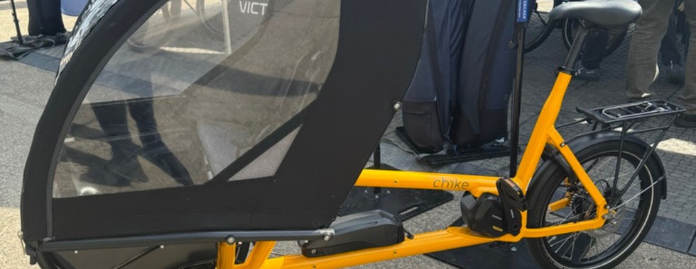 gelbes Lastenrad mit Regenverdeck zum Personentransport