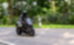 Motorradfahrer auf e-Motorrad fährt auf Landstraße durch Wald