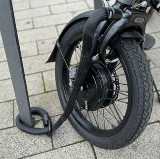 Textilschloß sicher e-Fahrzeug mit Nabenmotor im Vorderrad an einem Haltebügel.