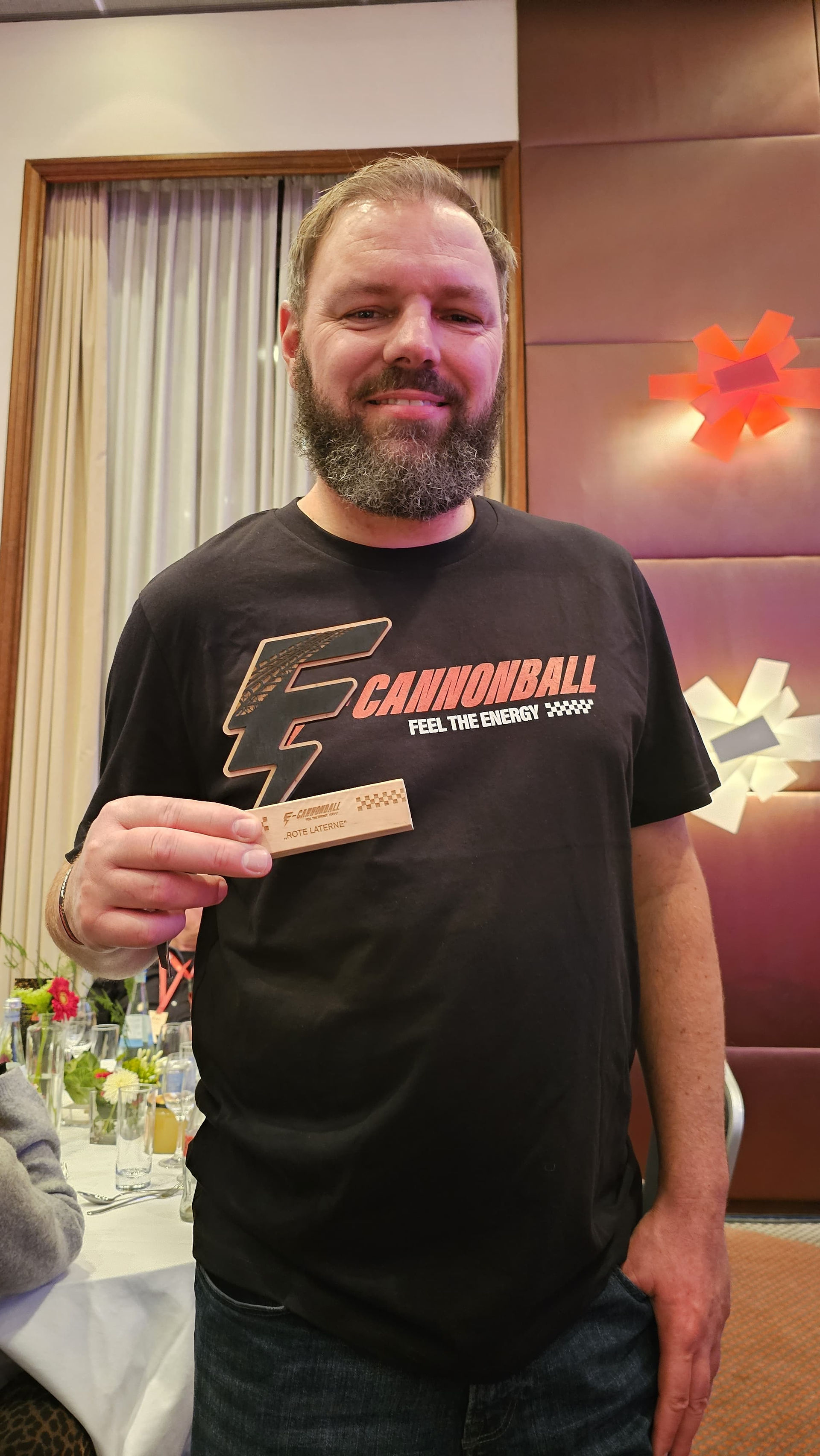 Mann mit T-Shirt E-Cannonball und Pokal