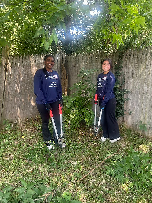 Two female students smiling while holding loppers.