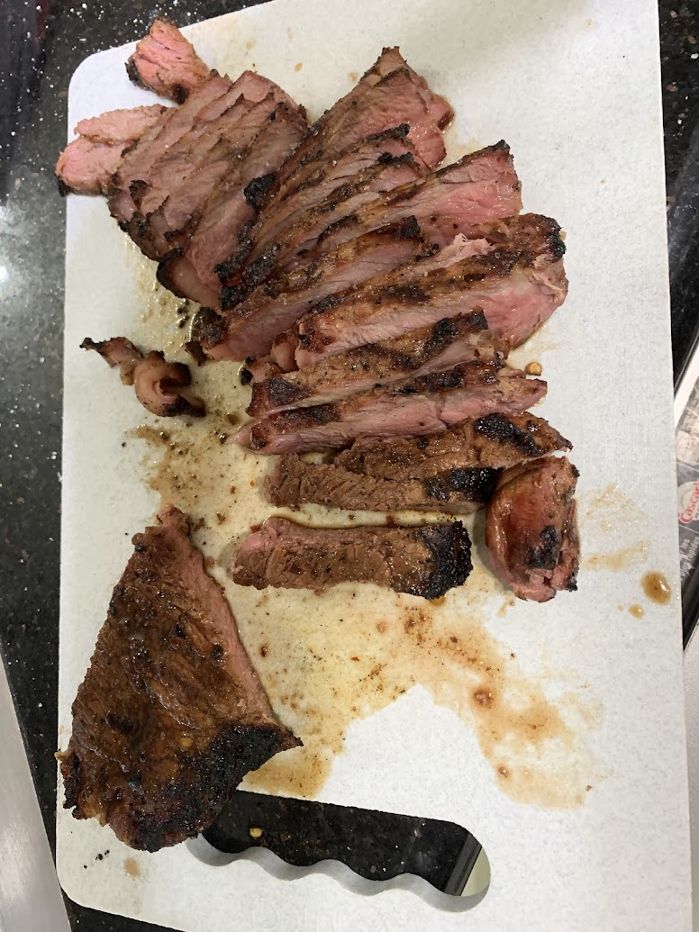 Sliced grilled steak on paper towels, juicy pink centers and charred edges on a countertop.