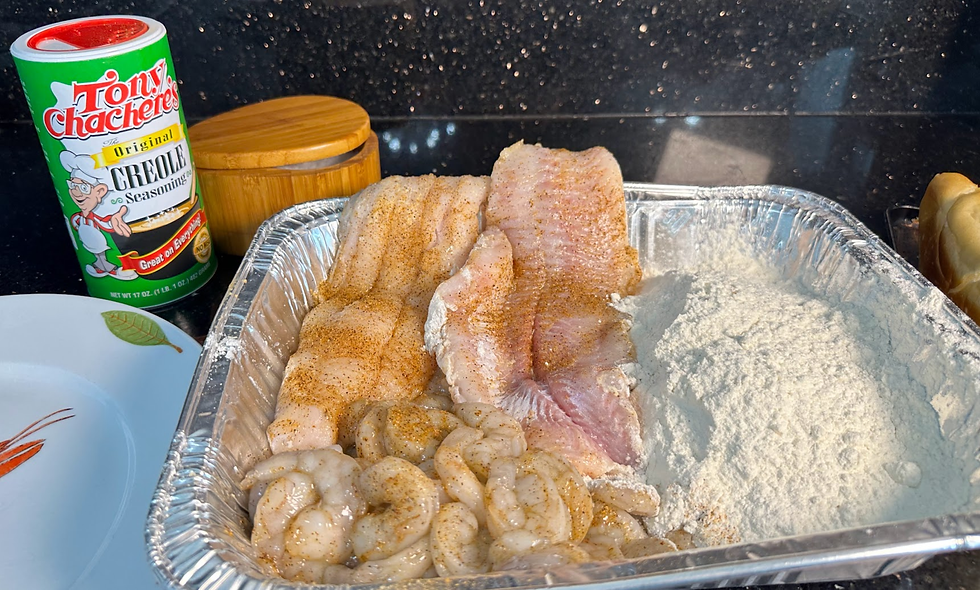 Aluminum tray with seasoned fish fillets, shrimp and flour beside Tony Chachere’s Creole seasoning on a kitchen counter.