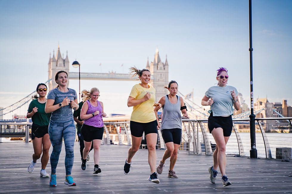 Female runners running along pavement with Tower Bridge in the background