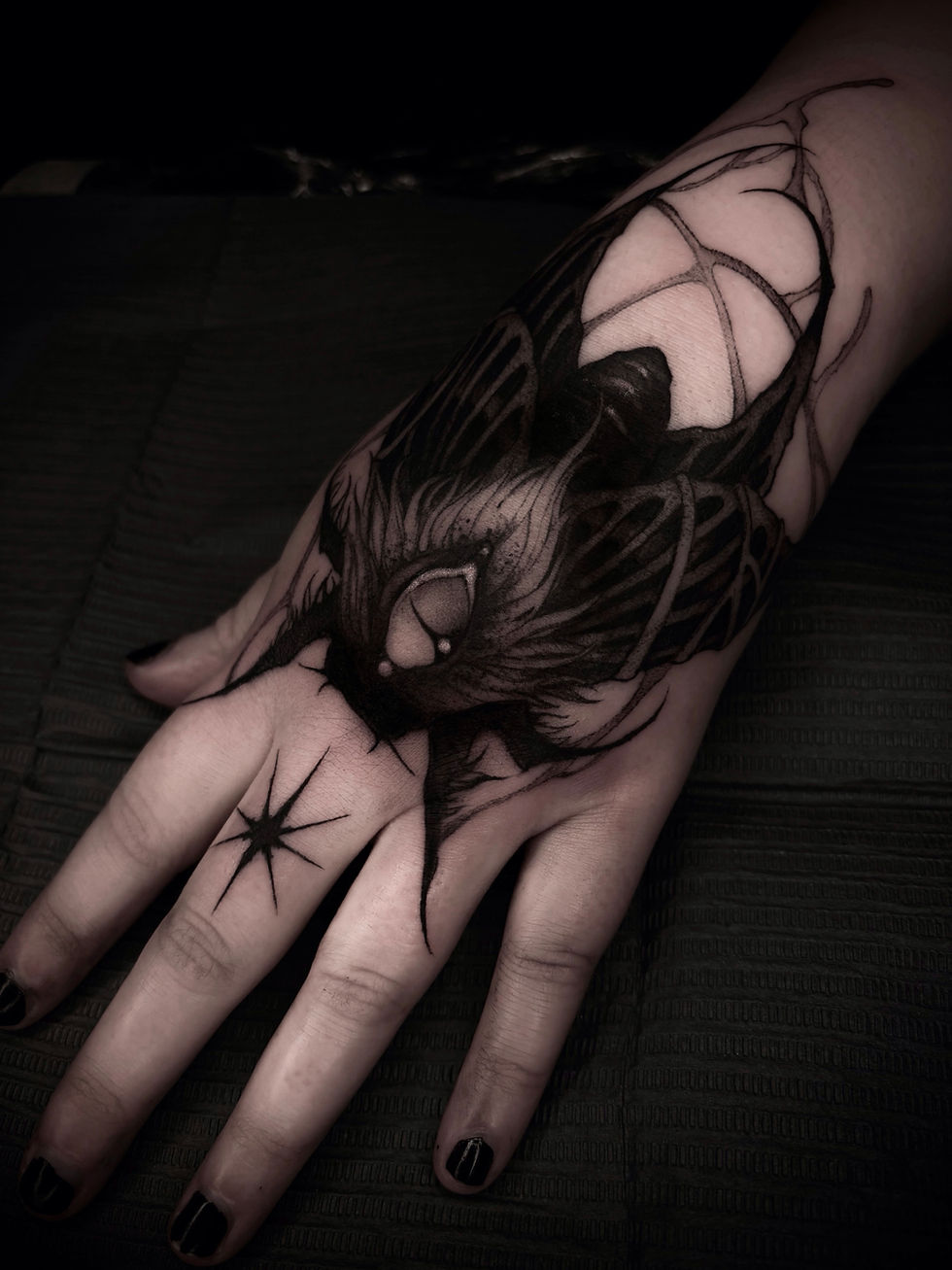 Black ink spider tattoo on hand and wrist.