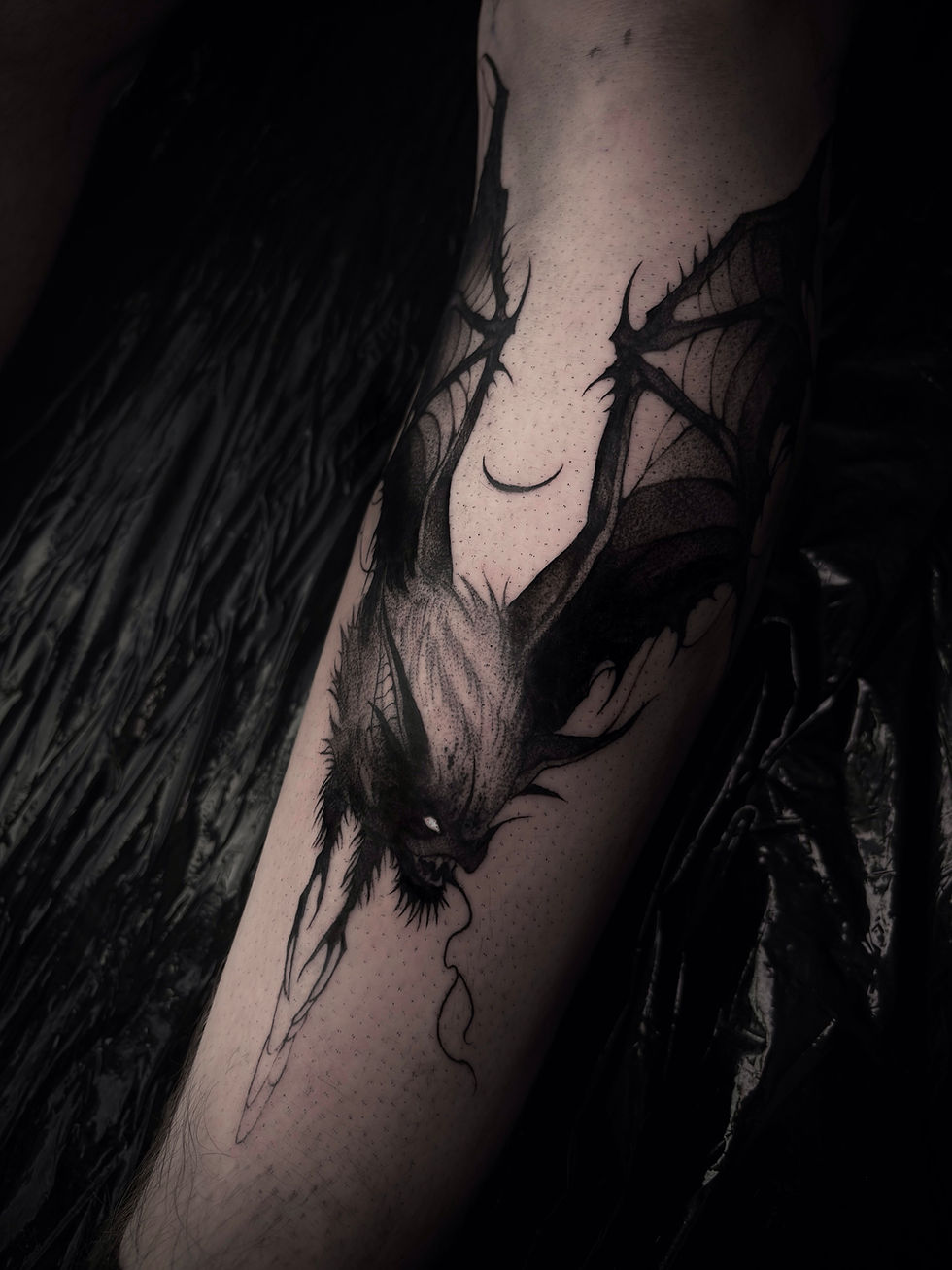 Black ink dark art tattoo on a forearm