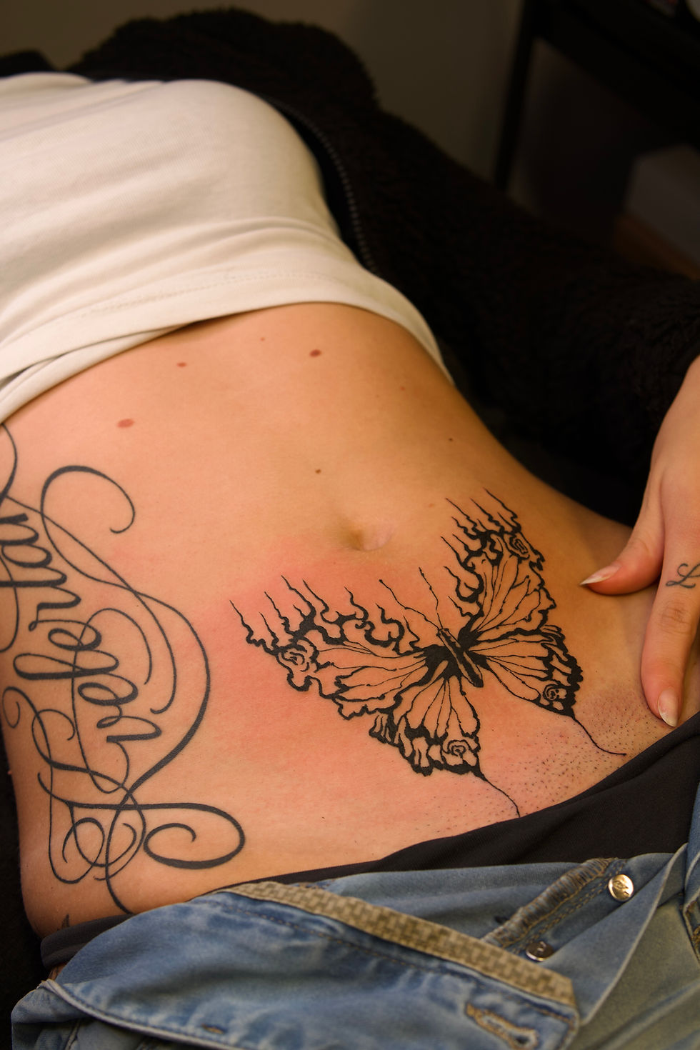 Butterfly and cursive script tattoos on a woman's torso