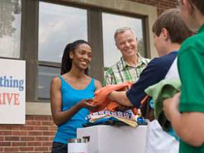 Two professionals volunteering at a clothing drive event.