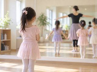 鏡の前に立つ小学生の女の子の後ろ姿のイメージ