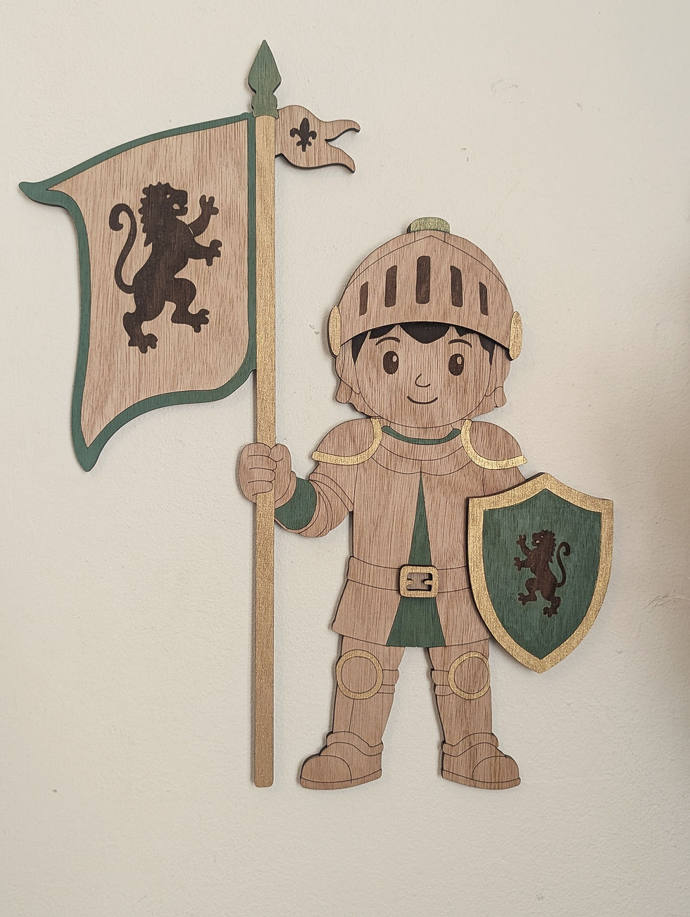 Décoration murale enfant en bois représentant un petit chevalier avec bouclier vert sauge et grand drapeau médiéval dans une