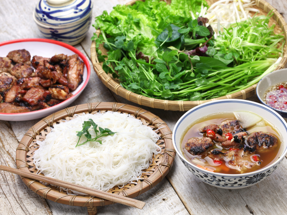 Hands holding chopsticks over bun cha with emotional expression