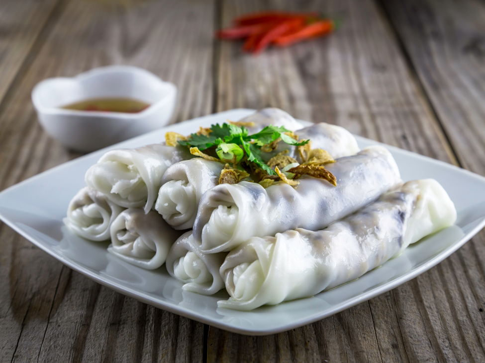 Freshly made banh cuon rice rolls being prepared by a street vendor.