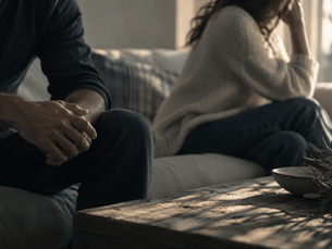 couple sit divided on a couch